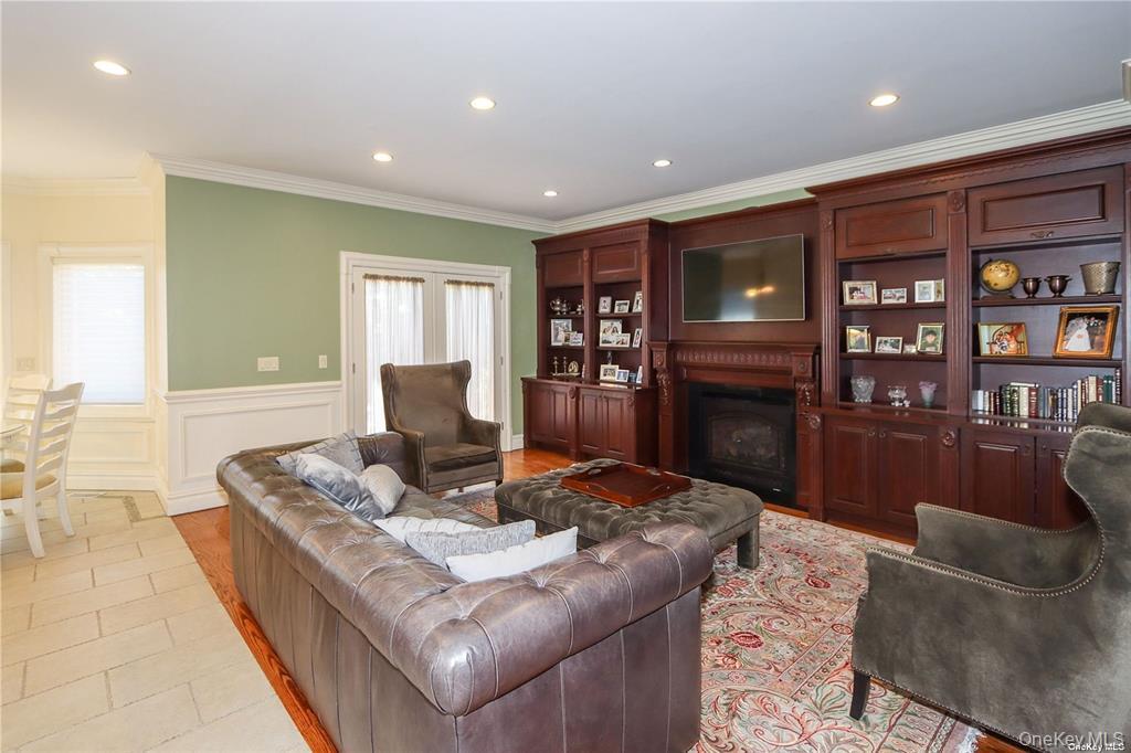24 Steamboat Road Great Neck, NY 11024 - Photo 6 of 28 Living area with crown molding, recessed lighting, a fireplace, a wainscoted wall, and a decorative wall