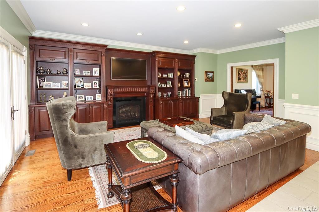 24 Steamboat Road Great Neck, NY 11024 - Photo 7 of 28 Living room with a fireplace, ornamental molding, recessed lighting, light wood-style flooring, and wainscoting