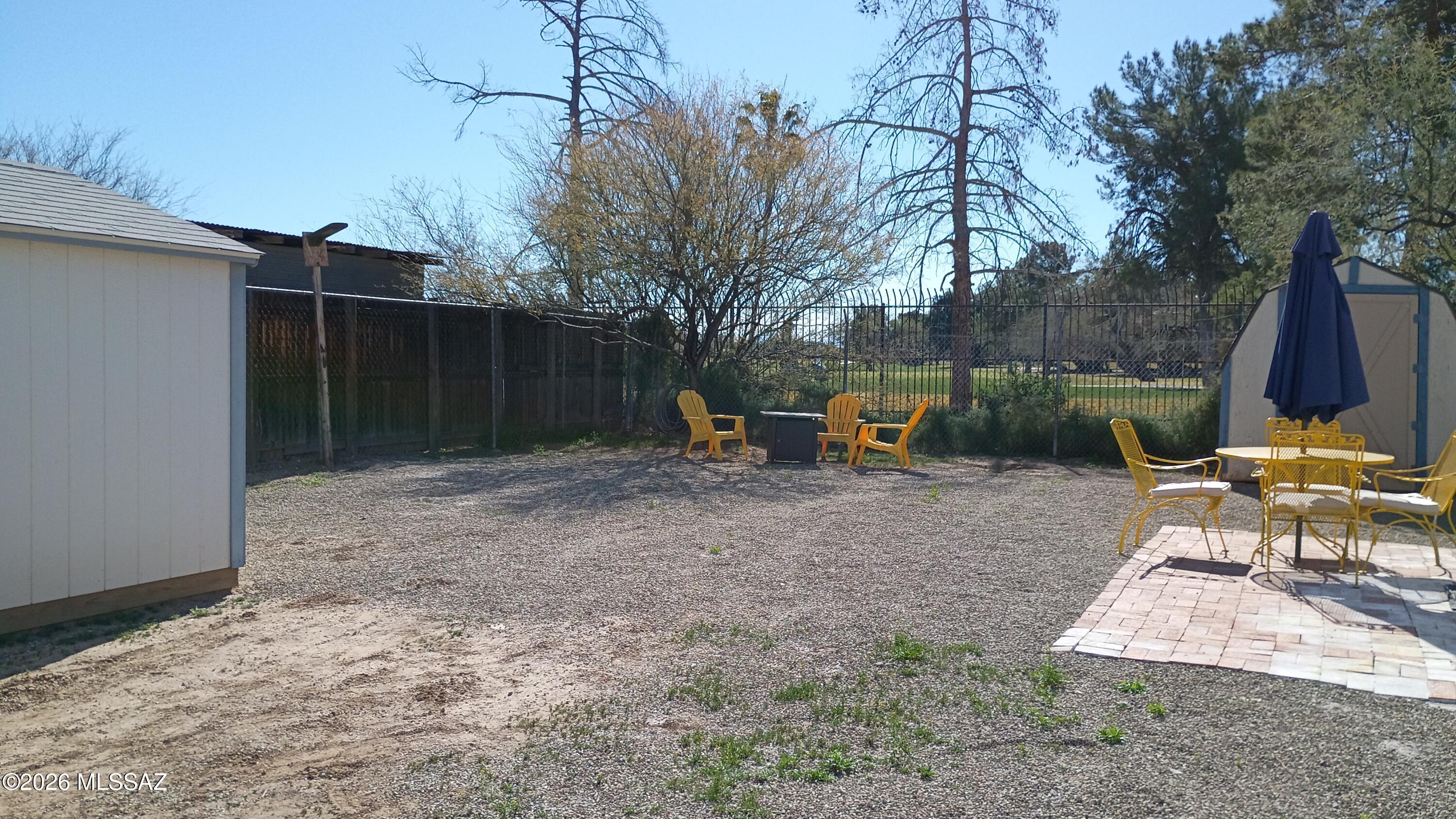 1449 West Hualpai Road Tucson, AZ 85745 - Photo 37 of 49 a view of backyard with table and chairs a fire pit and wooden fence