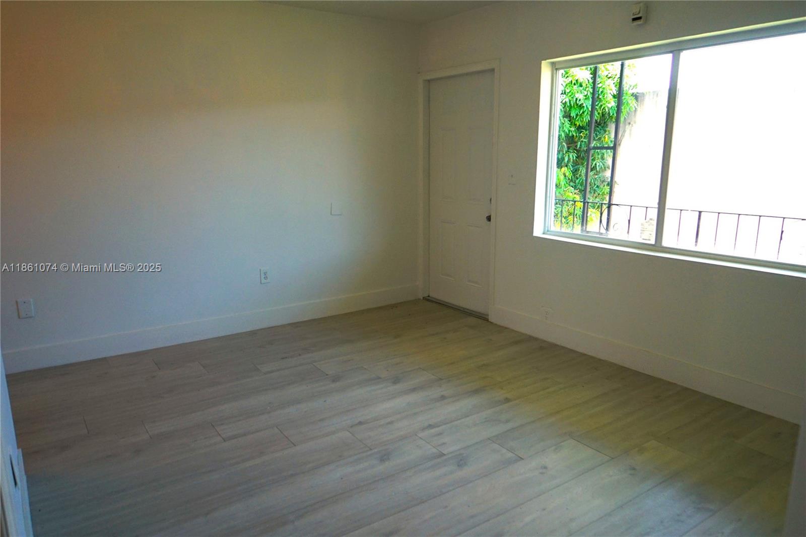 584 Northwest 65th Street, Unit 11 Miami, FL 33150 - Photo 2 of 8 an empty room with wooden floor and windows