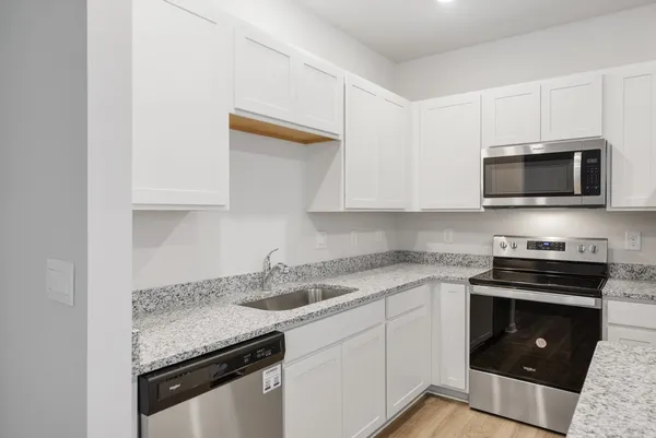 a kitchen with stainless steel appliances granite countertop a sink stove and microwave