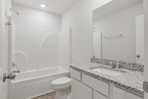a bathroom with a granite countertop sink a toilet and shower