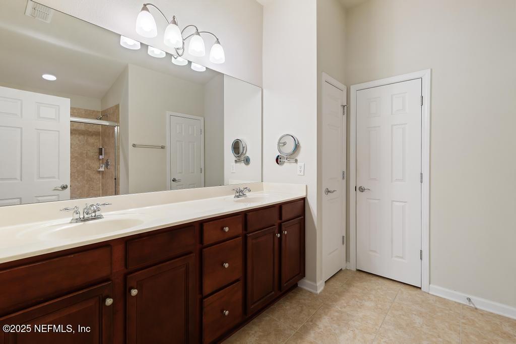 9080 Sweet Tree Trail Jacksonville, FL 32256 - Photo 16 of 44 a spacious bathroom with a double vanity sink a large mirror and shower