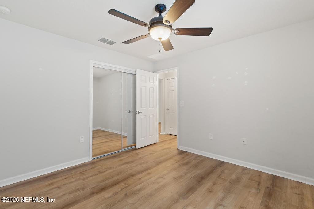 9080 Sweet Tree Trail Jacksonville, FL 32256 - Photo 21 of 44 an empty room with wooden floor ceiling fan and window