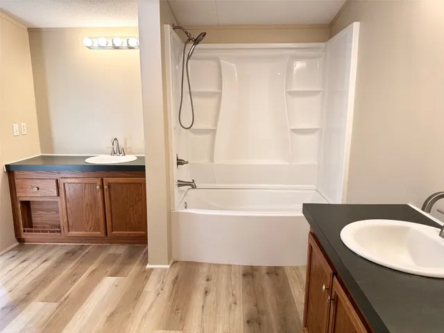 a bathroom with a sink vanity granite tub shower and a mirror