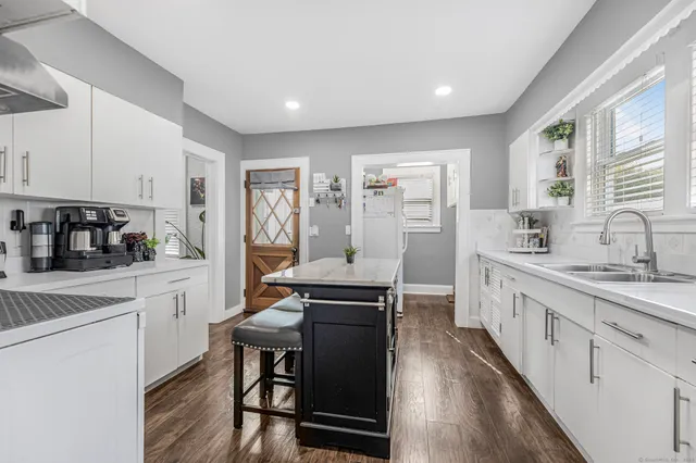 a kitchen with stainless steel appliances granite countertop a stove a sink dishwasher and cabinets with wooden floor