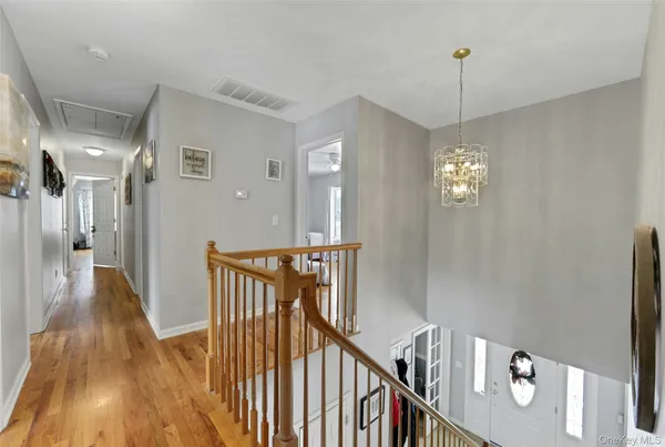 a view of a hallway with wooden floor and chandelier
