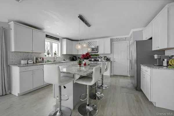 a kitchen with kitchen island a dining table chairs refrigerator and cabinets