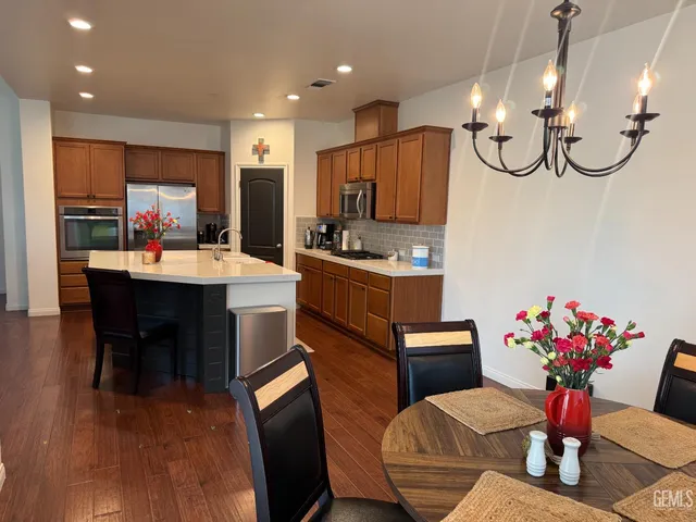 a kitchen with stainless steel appliances kitchen island granite countertop a table chairs in it and wooden floors