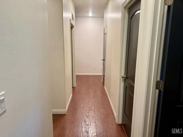 a view of a hallway with wooden floor and a bathroom