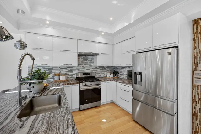 a kitchen with stainless steel appliances granite countertop a stove top oven a sink dishwasher a refrigerator and cabinets with wooden floor