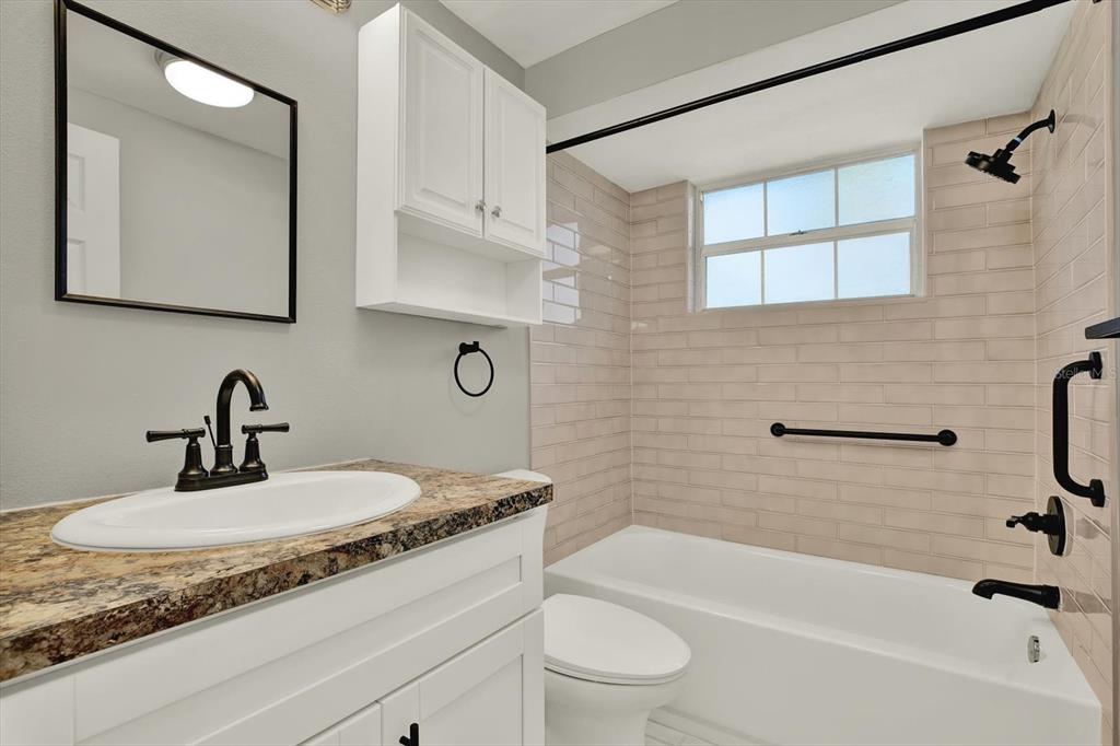 4455 Rustic Drive New Port Richey, FL 34652 - Photo 20 of 27 a bathroom with a granite countertop sink a toilet a mirror and bathtub