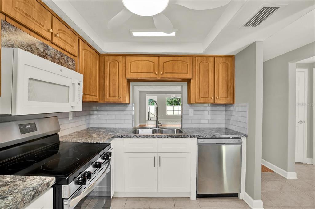 4455 Rustic Drive New Port Richey, FL 34652 - Photo 5 of 27 a kitchen with granite countertop a stove a sink and a microwave
