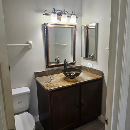a bathroom with a granite countertop sink toilet and mirror