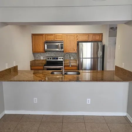 a living room with stainless steel appliances a sink a counter top space and cabinets