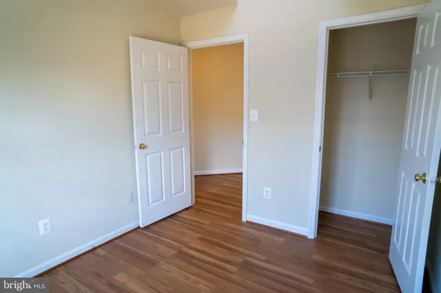 an empty room with wooden floor & closet area