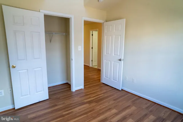 an empty room with wooden floor & closet area