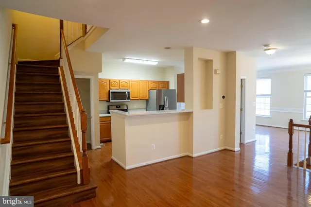 a view of a kitchen and an empty room with wooden floor