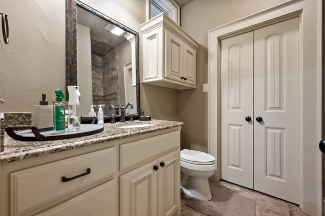 a bathroom with a granite countertop sink a toilet and a mirror