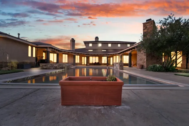 a view of a blue swimming pool with a yard