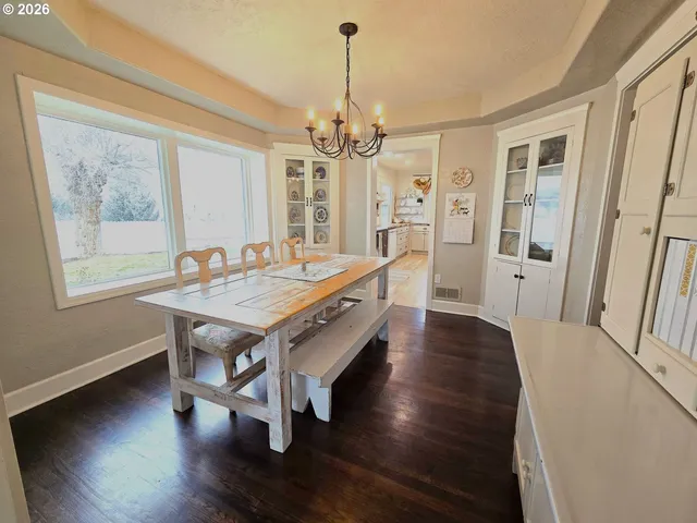 a dining room with wooden floor a chandelier a wooden table and chairs