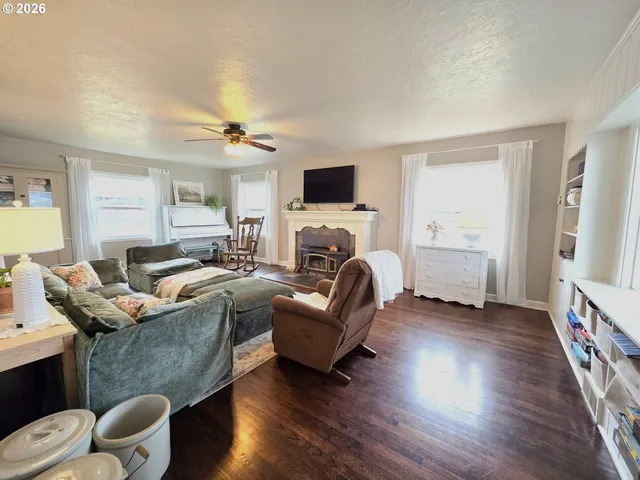 a living room with furniture hard wood floor and a ceiling fan
