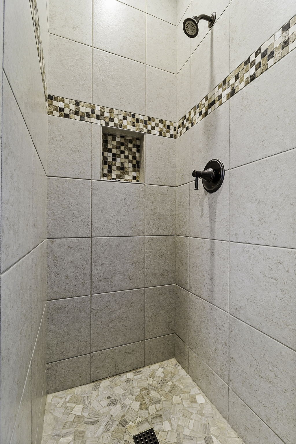 151 Key Largo Loop Point Blank, TX 77364 - Photo 34 of 49 Custom walk-in tiled shower featuring decorative mosaic accents, pebble-style flooring, and built-in shower niche off the covered back porch.