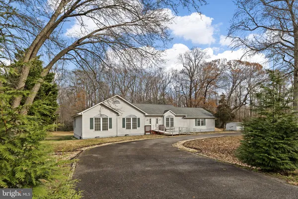 a view of white house with a large tree and wooden fence