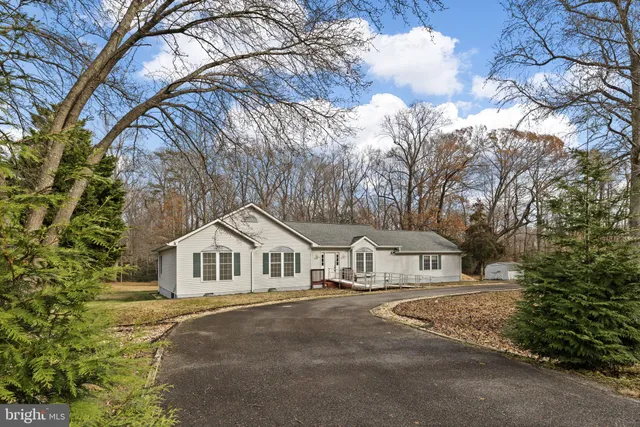 a view of white house with a large tree and wooden fence