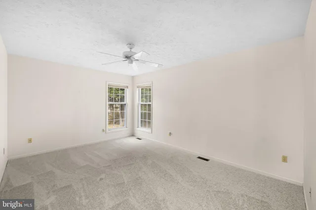 an empty room with a window and a ceiling fan