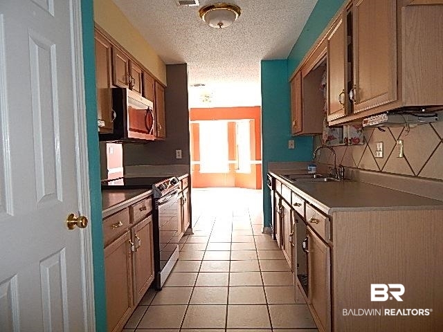 114 Pennbrooke Loop Foley, AL 36535 - Photo 17 of 23 Kitchen with stainless steel appliances, a textured ceiling, sink, tasteful backsplash, and light tile patterned flooring