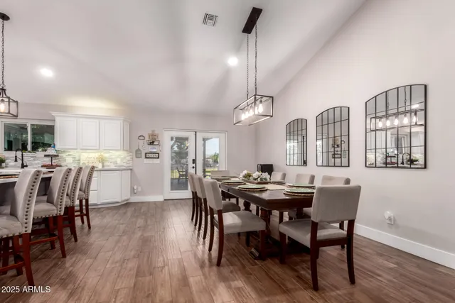 a dining room with wooden floor a chandelier a wooden table and chairs