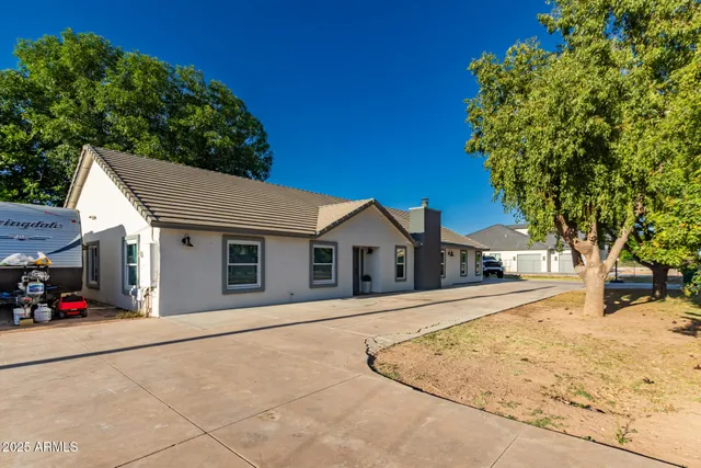 a view of a white house with a large tree
