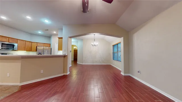 an empty room with wooden floor fireplace and windows