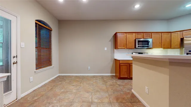 an empty room with wooden floor a ceiling fan and kitchen view