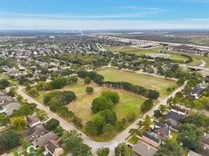 an aerial view of residential houses with outdoor space and trees