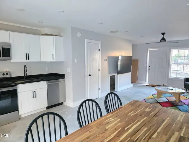 a kitchen with stainless steel appliances granite countertop a stove a sink a dining table and chairs