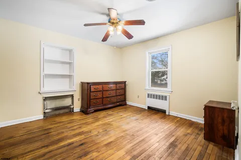 an empty room with wooden floor closet and windows