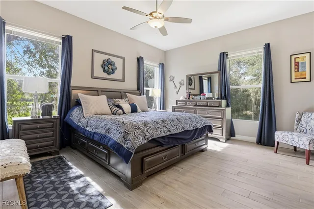 a bedroom with a bed painting on wall and a large window