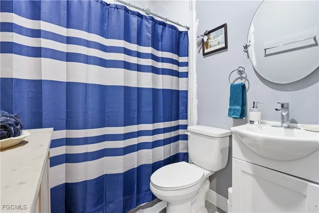 a bathroom with a sink a toilet a mirror and shower curtain