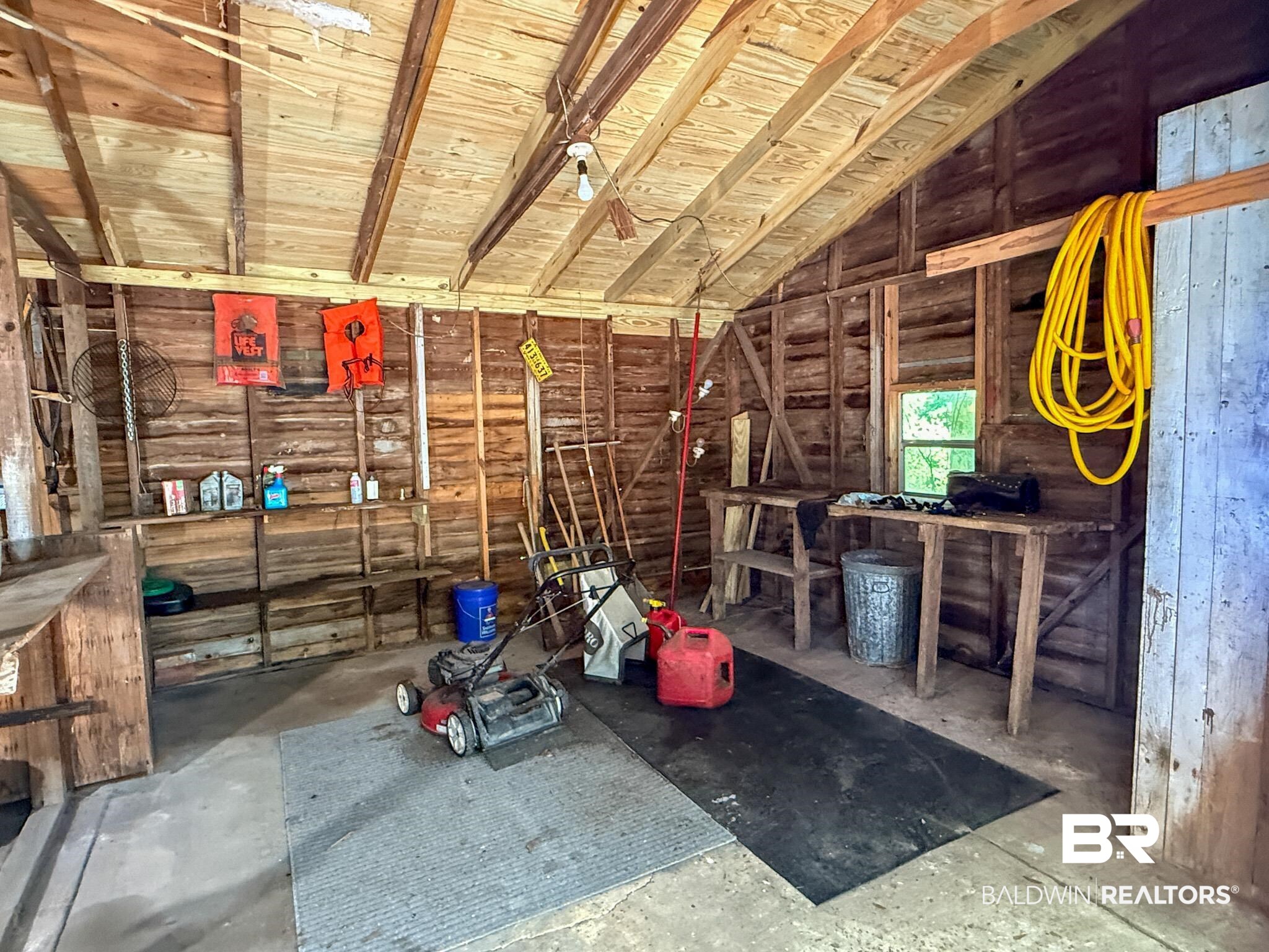 18711 Keller Road Foley, AL 36535 - Photo 35 of 38 Utility building featuring exposed wood beam construction, a concrete floor, built-in shelving, and a single-pane window