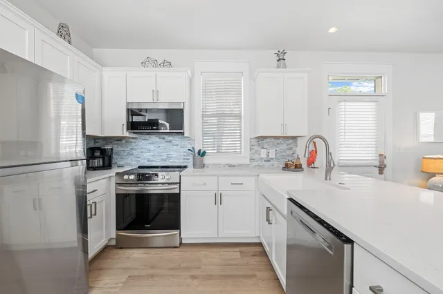 a kitchen with a sink and a stove with white cabinets