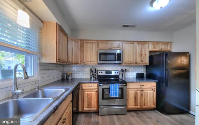 a kitchen with stainless steel appliances granite countertop a sink a stove a refrigerator cabinets and a window