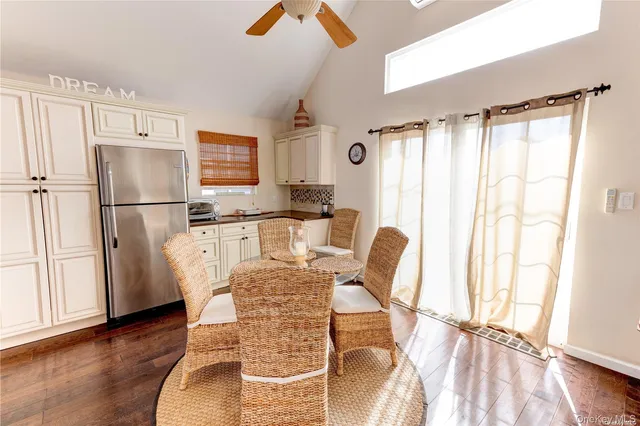 a kitchen with granite countertop a refrigerator a stove a sink cabinetry and a dining table