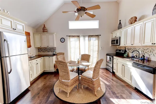 a kitchen with stainless steel appliances granite countertop a refrigerator a stove a sink dishwasher and white cabinets with wooden floor