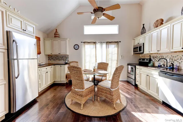 a kitchen with stainless steel appliances granite countertop a refrigerator a stove a sink dishwasher and white cabinets with wooden floor