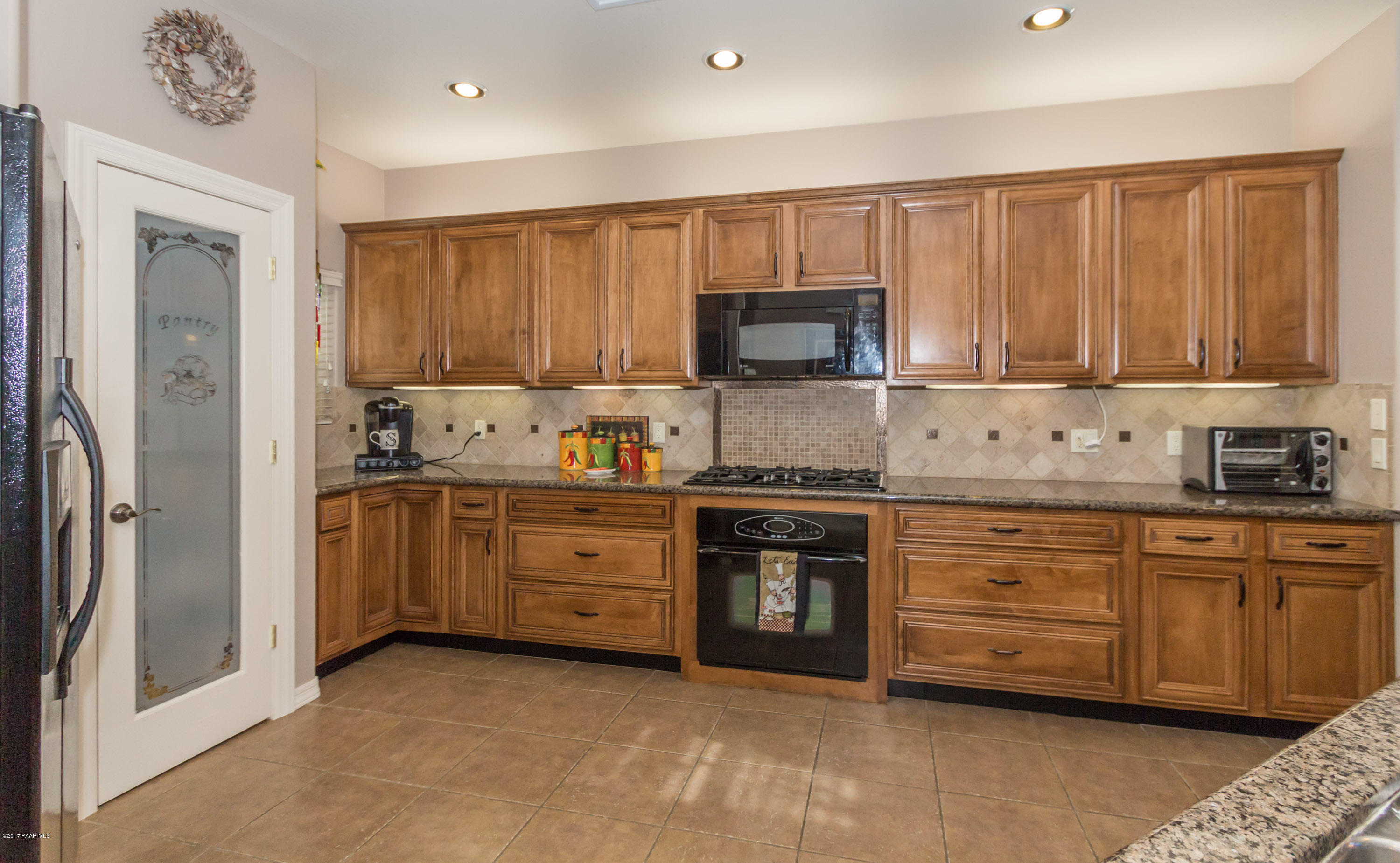 1256 Crown Ridge Drive Prescott, AZ 86301 - Photo 10 of 31 a kitchen with granite countertop a stove top oven sink and cabinets