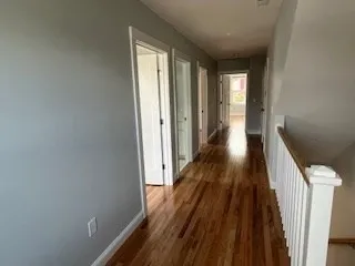 a view of a hallway with wooden floor and staircase