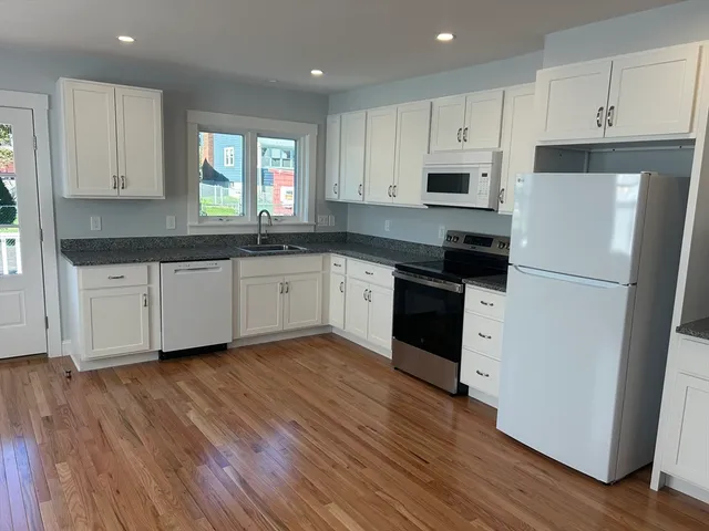 a kitchen with granite countertop white cabinets and wooden floor
