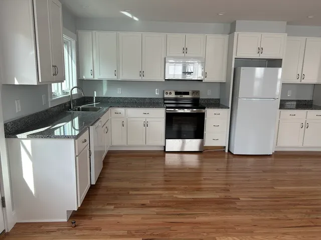 a kitchen with granite countertop a refrigerator and a stove top oven